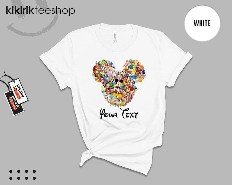 Pu&ograve; includere: T-shirt bianca con un colorato design a forma di testa di Topolino composto da vari personaggi dei cartoni animati. Il testo "Your Text" &egrave; stampato sotto. La maglietta ha maniche corte e girocollo.