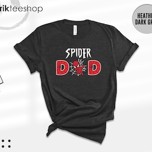 May include: A heather dark grey short-sleeve t-shirt featuring the white text SPIDER above the word DAD, where the letter A is replaced by a red and black spider-themed graphic with a web design inside the letters D and D.