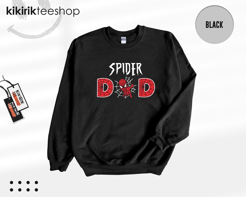 May include: A black long-sleeve crewneck sweatshirt featuring the white text SPIDER above the word DAD, where the letter A is replaced by a red and black spider-themed graphic with a web design. The sweatshirt has a ribbed collar and cuffs.