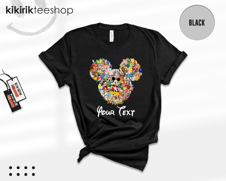 Pu&ograve; includere: T-shirt nera con un disegno a forma di testa di Topolino composto da vari personaggi dei cartoni animati. Le parole "Your Text" sono stampate in bianco sotto. La maglietta ha un girocollo e maniche corte.