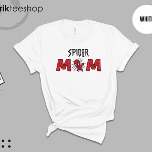 Puede incluir: Camiseta blanca con el texto "SPIDER MOM" en negro y rojo, con un dise&ntilde;o de Spider-Man. La camiseta tiene cuello redondo y mangas enrolladas. La marca "kikirikteeshop" es visible en la parte superior izquierda.