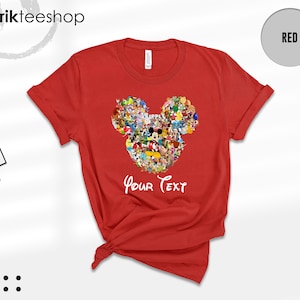 Pu&ograve; includere: Una maglietta rossa con un disegno della testa di Topolino composto da vari personaggi dei cartoni animati. Le parole "Your Text" sono scritte in bianco sotto. La maglietta ha le maniche arrotolate.