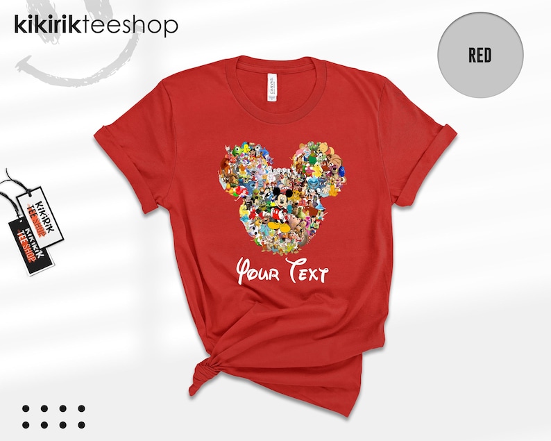 Pu&ograve; includere: Una maglietta rossa con un disegno della testa di Topolino composto da vari personaggi dei cartoni animati. Le parole "Your Text" sono scritte in bianco sotto. La maglietta ha le maniche arrotolate.