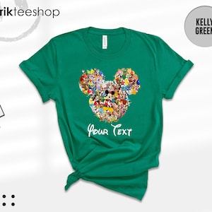 Pu&ograve; includere: T-shirt verde Kelly con un design a forma di testa di Topolino riempito con vari personaggi dei cartoni animati. Le parole "Your Text" sono scritte in bianco sotto. La maglietta ha un girocollo e maniche corte.