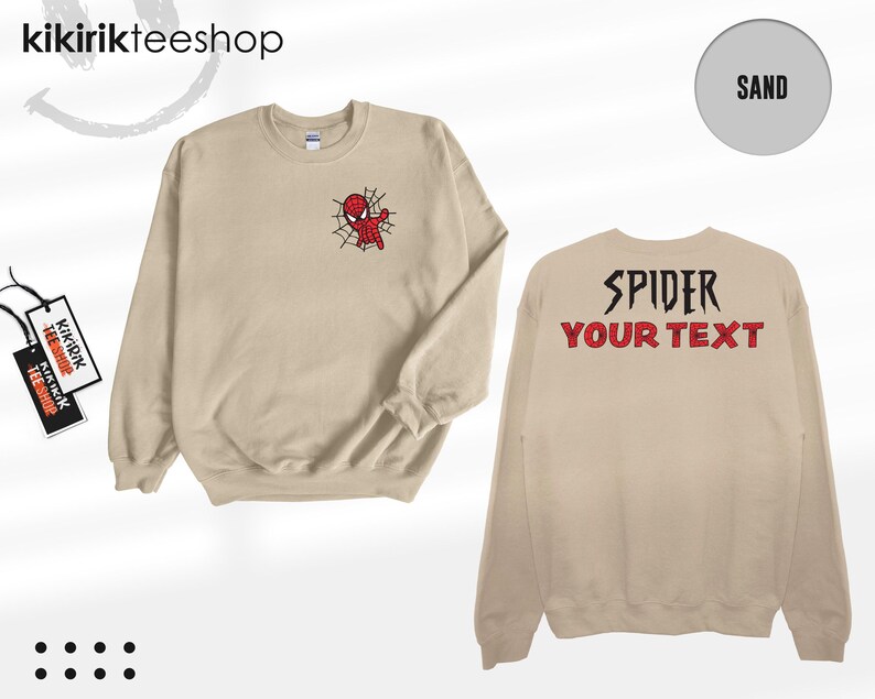 May include: A sand-colored crewneck sweatshirt featuring a small embroidered red and blue spider-themed character on the left chest. The back displays the black text SPIDER and the red text YOUR TEXT in a bold, stylized font.
