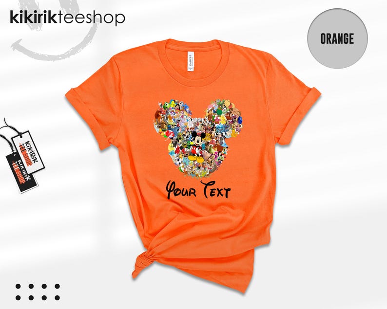 Pu&ograve; includere: T-shirt arancione brillante con un design a forma di testa di Topolino composto da personaggi dei cartoni animati. Il testo "Your Text" &egrave; stampato sotto. La maglietta ha un girocollo e maniche arrotolate.