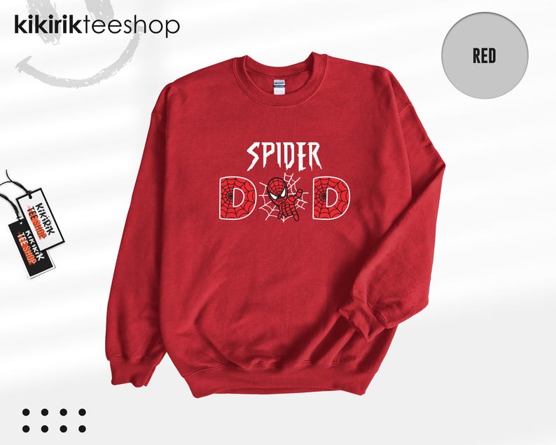 May include: A red crewneck sweatshirt featuring the white text SPIDER DAD on the chest. The letter A is replaced by a small red and blue spider-themed character, and the letters D are filled with a white spiderweb pattern. The brand tag is visible.
