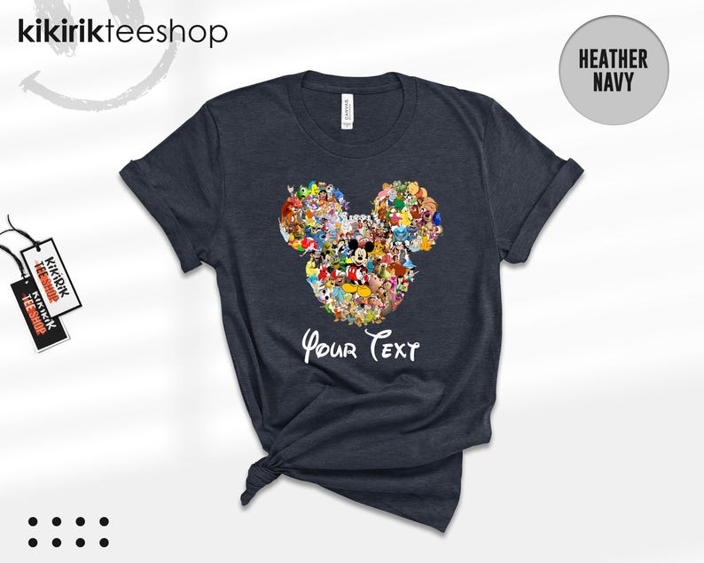 Pu&ograve; includere: T-shirt blu navy melange con un design a forma di testa di Topolino composto da vari personaggi dei cartoni animati. Le parole "Your Text" sono scritte in bianco sotto il disegno. La maglietta ha le maniche arrotolate e l'orlo annodato.