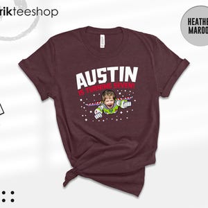 K&ouml;nnte beinhalten: Ein heather-maroonfarbenes T-Shirt mit dem wei&szlig;en Schriftzug AUSTIN und dem roten Text IS TURNING SEVEN! &uuml;ber einer Grafik eines Kindergesichts auf einem Weltraum-Ranger-Anzug mit Fl&uuml;geln, umgeben von kleinen wei&szlig;en Sternen auf dunklem Grund.