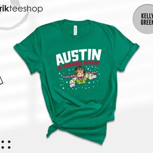 K&ouml;nnte beinhalten: Ein kellygr&uuml;nes Kurzarm-T-Shirt mit einer Grafik eines Kindes, das als Weltraum-Ranger verkleidet ist und mit Fl&uuml;geln fliegt. Der Text AUSTIN IS TURNING SEVEN! steht in wei&szlig;en und roten Buchstaben, umgeben von kleinen wei&szlig;en Sternen auf der Vorderseite.