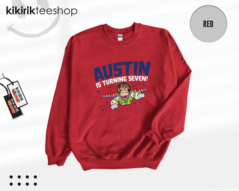 K&ouml;nnte beinhalten: Ein rotes Sweatshirt mit Rundhalsausschnitt und einer Grafik eines Kindes im Weltraum-Ranger-Kost&uuml;m mit Fl&uuml;geln. Der Text AUSTIN IS TURNING SEVEN! ist in blauen Buchstaben gedruckt. Das Design enth&auml;lt kleine blaue Sterne auf der Vorderseite.