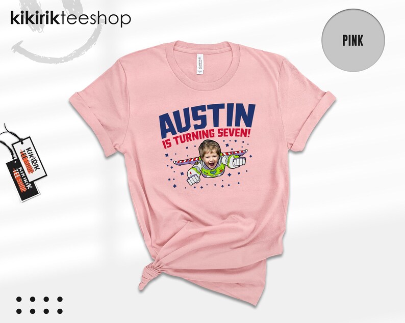 K&ouml;nnte beinhalten: Ein hellrosa T-Shirt mit kurzen &Auml;rmeln und einer Grafik, die das Gesicht eines Kindes auf dem K&ouml;rper einer Weltraum-Ranger-Figur zeigt. Der Text AUSTIN IS TURNING SEVEN! steht in blauen und roten Buchstaben, umgeben von kleinen blauen Sternen.