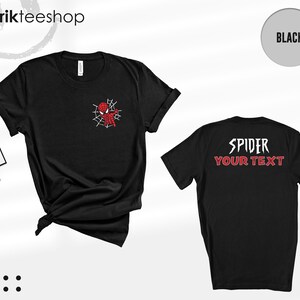 May include: A black short-sleeve t-shirt featuring a small red and black spider-themed character graphic on the left chest. The back of the shirt displays the white text SPIDER above the red text YOUR TEXT in a stylized, jagged font.