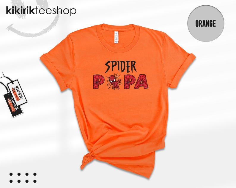 Puede incluir: Camiseta naranja brillante con las palabras "SPIDER PA" en negro y rojo, con una telara&ntilde;a y un gr&aacute;fico de ara&ntilde;a. La camiseta tiene las mangas enrolladas y una etiqueta que dice "kikirikteeshop".