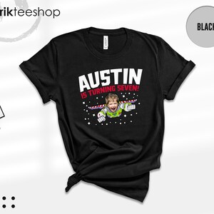 K&ouml;nnte beinhalten: Ein schwarzes Kurzarm-T-Shirt mit einer Grafik, die das Gesicht eines Kindes auf einem Weltraum-Ranger-Anzug zeigt. Der Text AUSTIN IS TURNING SEVEN! ist in wei&szlig;er und roter Schrift gehalten, umgeben von kleinen wei&szlig;en Sternen.