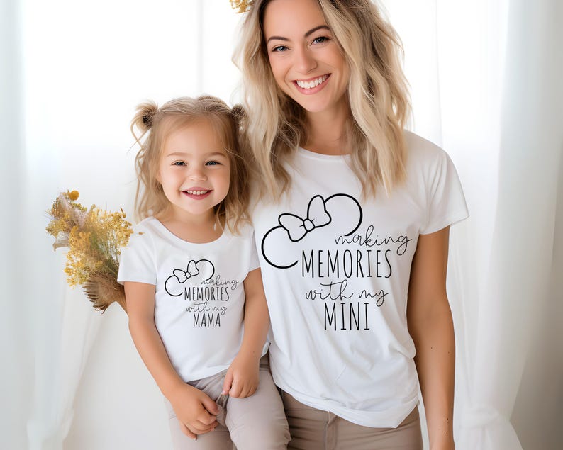 K&ouml;nnte beinhalten: Eine Mutter und ihre Tochter tragen wei&szlig;e T-Shirts mit schwarzem Text und einer Mickey-Maus-Silhouette. Das Shirt der Mutter lautet "Making Memories with my Mini" und das Shirt der Tochter lautet "Making Memories with my Mama".