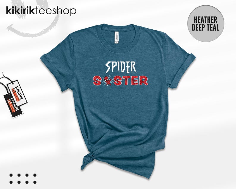 Puede incluir: Camiseta de color verde azulado oscuro con las palabras "SPIDER SISTER" en letras blancas y rojas. Un peque&ntilde;o gr&aacute;fico de una ara&ntilde;a est&aacute; entre las palabras. La camiseta est&aacute; anudada en la parte inferior.