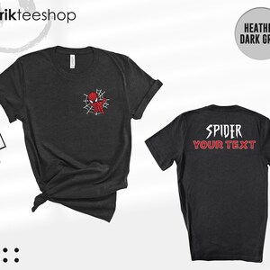 May include: A heather dark grey short-sleeve t-shirt featuring a small red spider-themed character graphic on the front left chest and the text SPIDER YOUR TEXT in white and red on the back. The shirt includes a branded tag attached to the side.