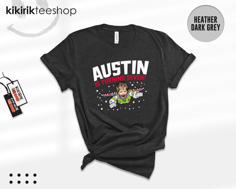 K&ouml;nnte beinhalten: Ein heather-dunkelgraues T-Shirt mit einer Grafik eines Kindes als Weltraum-Ranger, das durch Sterne fliegt. Der Text lautet AUSTIN IS TURNING SEVEN! in wei&szlig;er und roter Schrift. Das T-Shirt hat kurze &Auml;rmel und einen Rundhalsausschnitt.