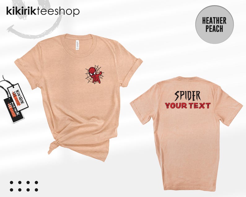 May include: A heather peach short-sleeve t-shirt featuring a small red and black spider-themed character graphic on the front left chest. The back of the shirt displays the text SPIDER and YOUR TEXT in a bold, dark, stylized font.