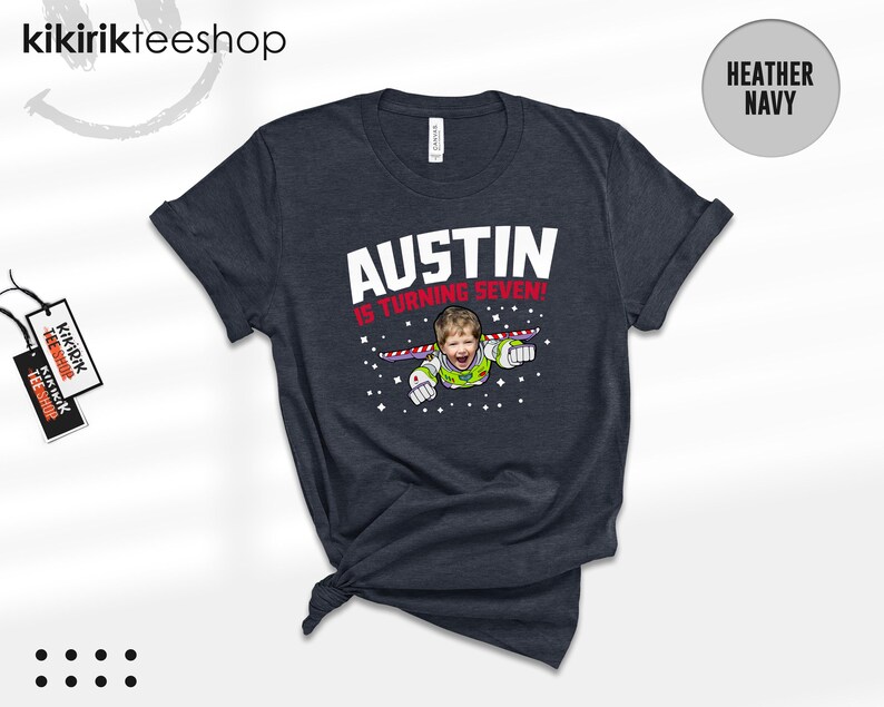 K&ouml;nnte beinhalten: Ein kurz&auml;rmeliges T-Shirt in Heather Navy mit einer Grafik eines Kindes in einem Weltraum-Ranger-Kost&uuml;m, das vor einem Sternenhintergrund fliegt. Der Text AUSTIN IS TURNING SEVEN! ist in Wei&szlig; und Rot gedruckt. Mit Rundhalsausschnitt.