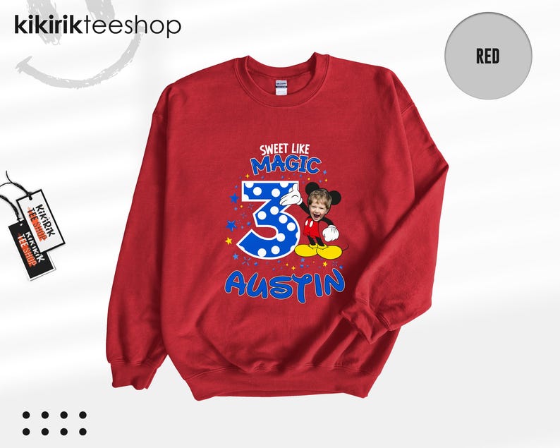 May include: A red crewneck sweatshirt featuring a graphic print with the text SWEET LIKE MAGIC, the number 3 in blue with white polka dots, and the name AUSTIN in blue. A cartoon character with a child's face is positioned next to the number 3.