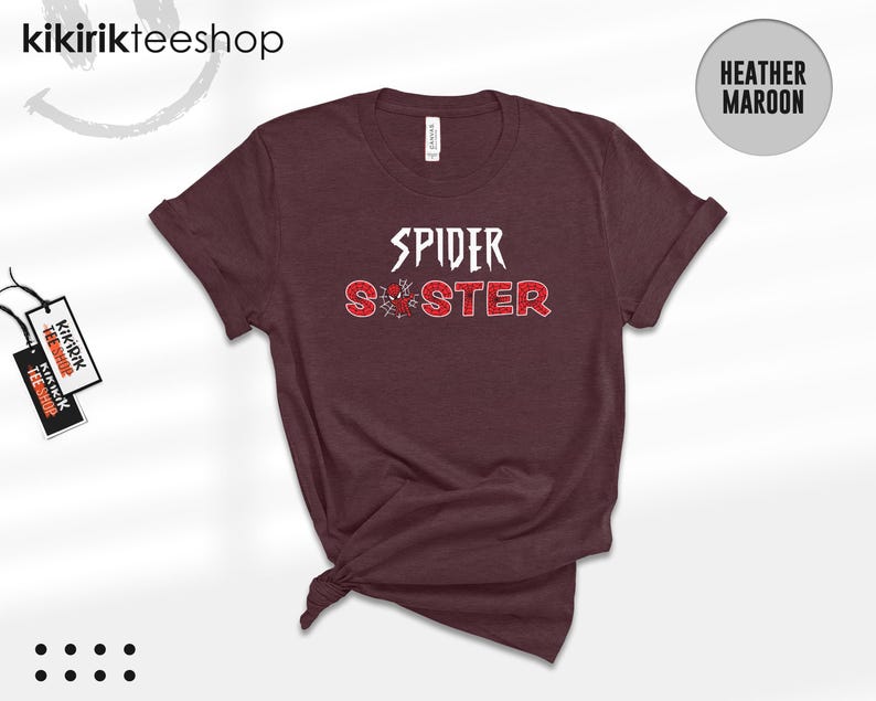 Puede incluir: Camiseta color granate jaspeado con las palabras "SPIDER SISTER" en letras blancas y rojas. La palabra "SPIDER" est&aacute; en negrita, y "SISTER" en un estilo desgastado. Un gr&aacute;fico de ara&ntilde;a est&aacute; entre las palabras, sobre un fondo granate.