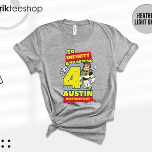 Puede incluir: Una camiseta gris jaspeado claro con un gr&aacute;fico que incluye el texto To Infinity and Beyond, un n&uacute;mero 4 grande de color amarillo y el nombre Austin Birthday Boy. El dise&ntilde;o muestra un personaje espacial con el rostro de un ni&ntilde;o.
