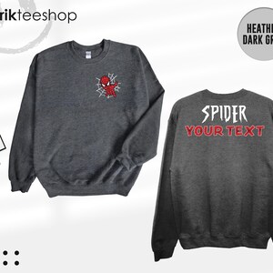 May include: A heather dark grey crewneck sweatshirt featuring a small red and blue spider-themed character graphic on the front left chest. The back displays the white text SPIDER above the red text YOUR TEXT in a stylized font.