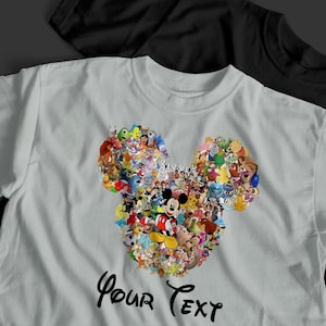 Pu&ograve; includere: Una maglietta grigio chiaro con un design a forma di testa di Topolino composto da vari personaggi Disney. Il testo "Your Text" &egrave; scritto in corsivo in basso. Una maglietta nera &egrave; visibile sullo sfondo.