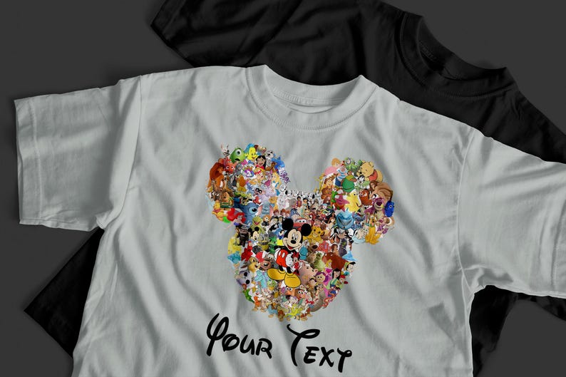Pu&ograve; includere: Una maglietta grigio chiaro con un design a forma di testa di Topolino composto da vari personaggi Disney. Il testo "Your Text" &egrave; scritto in corsivo in basso. Una maglietta nera &egrave; visibile sullo sfondo.