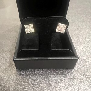 May include: A pair of square-shaped diamond earrings in a black velvet jewelry box.