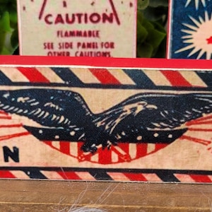 May include: Red, white, and blue wooden sign with a bald eagle and fireworks. The sign reads "Made in U.S.A."