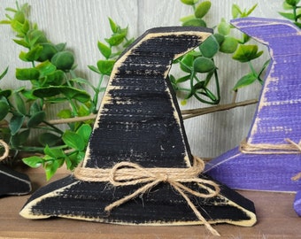 May include: A black wooden witch hat with a brown twine bow. The hat is distressed and has a rustic look.
