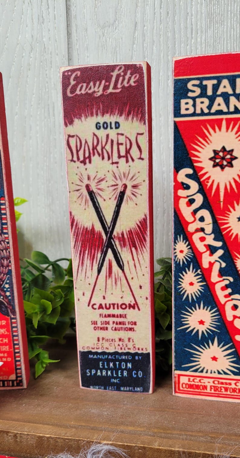 May include: Vintage red, white, and blue Easy Lite Gold Sparkler box with the text "CAUTION FLAMMABLE" and "MANUFACTURED BY ELKTON SPARKLER CO. INC. NORTH EAST MARYLAND".