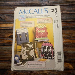 May include: McCall's sewing pattern for beginner backpack designs. The pattern features instructions for various backpack styles, including a camouflage print, a pink polka dot, and a black and white giraffe print. The pattern includes the text "Learn to Sew for Fun".