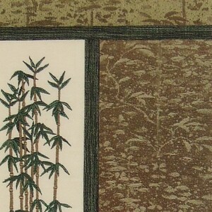 May include: A close-up of a cream-coloured fabric with an embroidered design of green bamboo stalks. The fabric is framed by a dark green border.