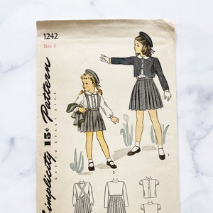 May include: Vintage Simplicity sewing pattern number 1242, size 6, for a girl's dress and jacket. The pattern includes a black and white checked skirt, a white blouse, and a black jacket. The pattern is printed on a white background with black text.
