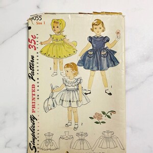 May include: Vintage Simplicity sewing pattern for a girl's dress. The pattern is for size 1 and includes three different dress styles. The pattern is printed on a white background with black text and illustrations. The text on the pattern reads "Simplicity Printed Pattern 35c Details Printed on Each Pattern Piece".