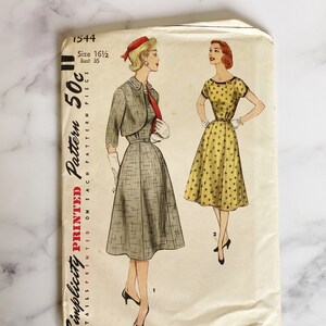 Könnte beinhalten: Vintage Simplicity Schnittmuster für ein Kleid und eine Bolerojacke. Das Schnittmuster ist auf weißes Papier mit einer gelblichen Tönung gedruckt. Die Schnittmuster-Nummer ist 1544 und die Größe ist 16 1/2. Die Brustweite beträgt 89 cm. Das Schnittmuster kostet 50 Cent.