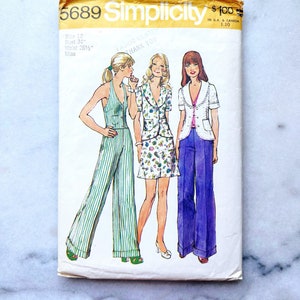 May include: Simplicity sewing pattern number 5689 for a miss size 12 with a bust measurement of 34 inches and a waist measurement of 26 1/2 inches. The pattern shows three different outfits: a striped jumpsuit, a floral print top with a matching skirt, and a white jacket with a purple pair of trousers.