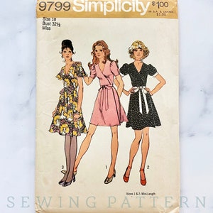 May include: Simplicity sewing pattern number 9799 for a mini-length dress with a wrap style. The pattern includes three views: one with a floral print, one in pink, and one with black and white polka dots. The pattern is for size 10, bust 32 1/2 inches, and is for misses.