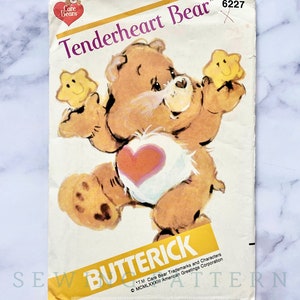 May include: A vintage sewing pattern for a Care Bear named Tenderheart Bear. The pattern is from Butterick and is number 6227. The pattern features a cartoon illustration of Tenderheart Bear holding a yellow star.