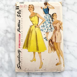 May include: Vintage Simplicity sewing pattern number 1180 for a dress. The pattern is for size 14 1/2, bust 33. The pattern shows three different styles of dresses, one yellow, one blue and white, and one striped.