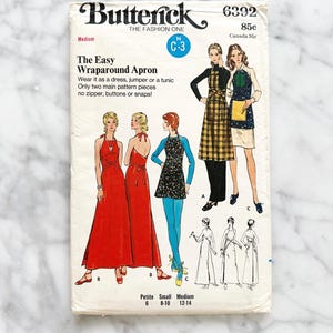 May include: Vintage sewing pattern for a wraparound apron, dress, or tunic. The pattern is from Butterick, pattern number 6392, and is for sizes 6-14. The pattern is for a simple design with only two main pattern pieces. The pattern is for a medium size.