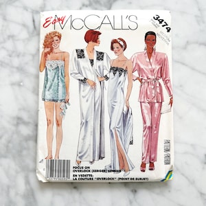Könnte beinhalten: Ein Schnittmuster für vier verschiedene Stile von Nachtwäsche. Das Schnittmuster ist für eine mittlere Größe und heißt McCall's Easy 3474. Das Schnittmuster beinhaltet ein kurzes Nachthemd, ein langes Nachthemd, einen Morgenmantel und einen Pyjama. Das Schnittmuster ist auf weißem Papier mit schwarzem Text und Illustrationen gedruckt.