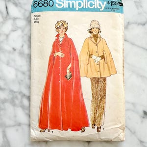 May include: Vintage Simplicity sewing pattern number 6680 for a cape. The pattern is for sizes 8-10 and is labeled "Small Miss". The pattern shows two women wearing different versions of the cape, one in red and one in brown.