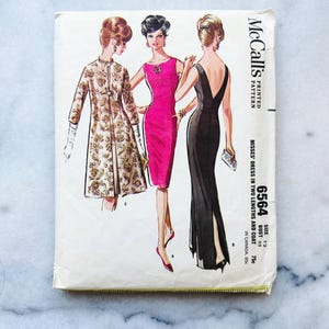 Puede incluir: Patrón de costura vintage McCall's 6564 para un vestido de mujer en dos largos y un abrigo. El patrón incluye instrucciones para un vestido rosa, un vestido negro y un abrigo dorado.