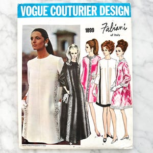 Puede incluir: Patrón de costura vintage Vogue Couturier Design de Fabiani de Italia. La portada muestra ilustraciones de mujeres con vestidos, incluyendo un abrigo blanco y un vestido negro. El texto "Vogue Couturier Design" está en una pancarta azul.