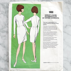 May include: Vintage Vogue sewing pattern guide. The cover shows illustrations of two women in white dresses. Text on the green background reads "Vogue's Guide to Perfect Fit of Fitted Garments". Misses' sizes 6-8-10-12-14-16-18-20.
